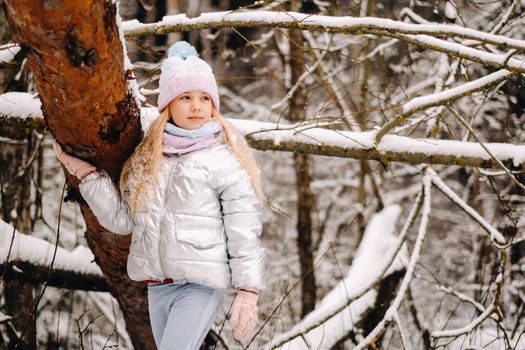 a little girl in a silver jacket in winter goes outside in winter.