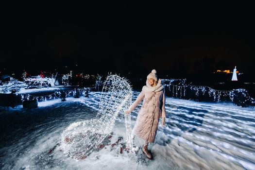 a girl in a gray jacket in winter with evening lights burning on Christmas street.