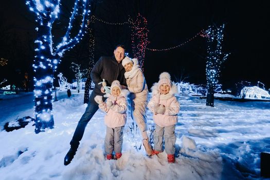 A large family with children in a Christmas city at night with night lights.