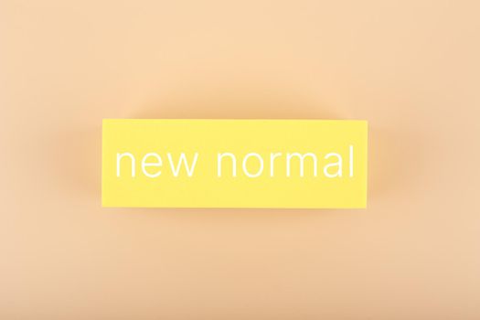 New normal concept. Text on yellow rectangle against pastel beige background. High quality photo