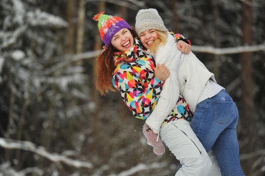 Two girls in the winter forest emotionally hug and smile.Happy women hug and Express joy.