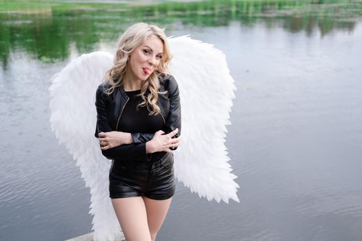 dark angel. blonde sexy woman in black leather clothes with white angels wings.