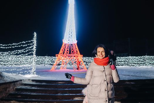 a girl in a gray jacket in winter with evening lights burning on Christmas street.