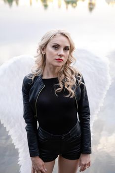 dark angel. blonde sexy woman in black leather clothes with white angels wings.