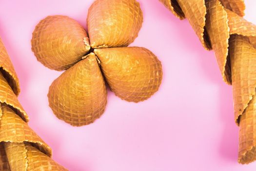 figures from waffle cones for ice cream on a pink background.
