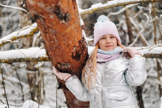 a little girl in a silver jacket in winter goes outside in winter.