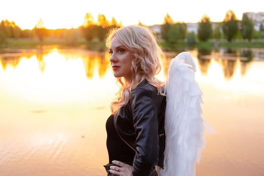 dark angel. blonde sexy woman in black leather clothes with white angels wings.