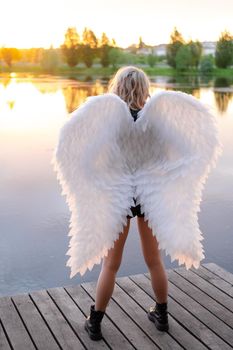 woman with white angel wings. wearing black leather clothes. fallen dark angel. demon. beast. girl in angel costume on halloween.