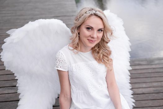 woman with white angel wings. beautiful blonde in angel costume. heaven, purity. good person.