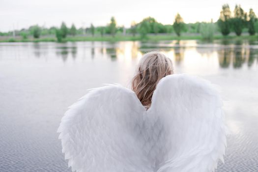 woman with white angel wings. beautiful blonde in angel costume. heaven, purity. good person.