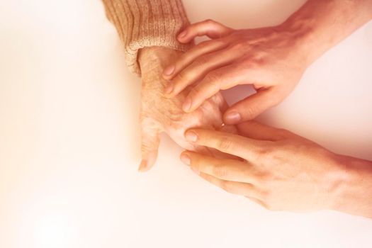 Young woman's hands hold grandmother's hands, an elderly patient. Handshake, caring, trust and support. Medicine, family and healthcare.