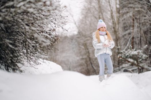 a little girl in a silver jacket in winter goes outside in winter.