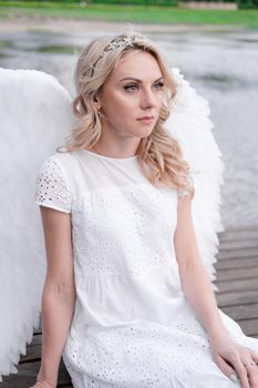 woman with white angel wings. beautiful blonde in angel costume. heaven, purity. good person.