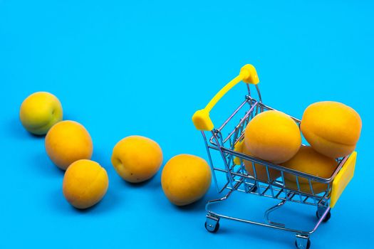 Shopping basket with apricots on a blue background.Shopping cart.