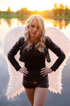 portrait of a sensitive woman with white angel wings. wearing black leather clothes. fallen dark angel. demon. beast