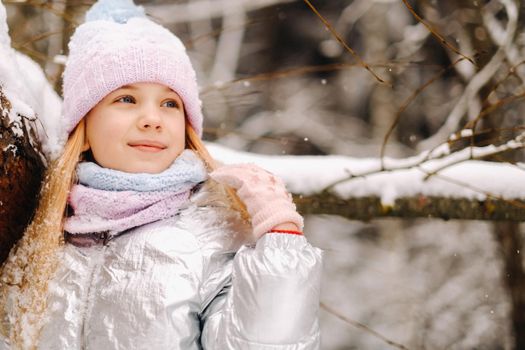 a little girl in a silver jacket in winter goes outside in winter.