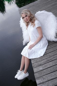 beautiful angel in white dress. Amazing blond woman with long curly hair and white wings