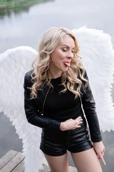 portrait of a sensitive woman with white angel wings. wearing black leather clothes. fallen dark angel. demon. beast