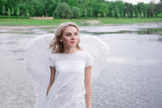 beautiful angel in white dress. Amazing blond woman with long curly hair and white wings