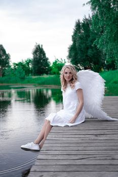 beautiful angel in white dress. Amazing blond woman with long curly hair and white wings