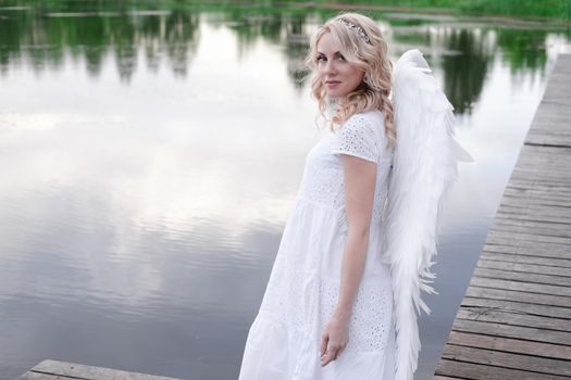 woman with white angel wings. beautiful blonde in angel costume. heaven, purity. good person.