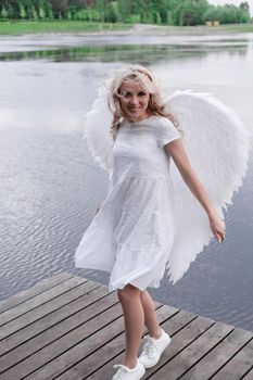 woman with white angel wings. beautiful blonde in angel costume. heaven, purity. good person.