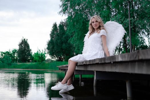 woman with white angel wings. beautiful blonde in angel costume. heaven, purity. good person.