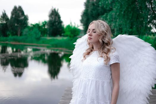 woman with white angel wings. beautiful blonde in angel costume. heaven, purity. good person.