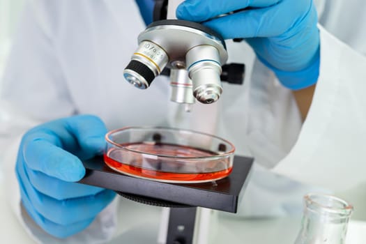 Asian scientist biochemist or microbiologist working research with a microscope in laboratory. For protect outbreak Coronavirus Covid19, bacteria and germs.