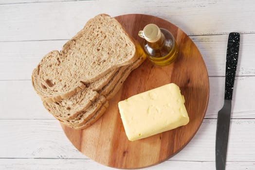 slice of butter and whole meal bread on chopping board .