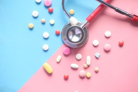 colorful medical pills and stethoscope on color background .