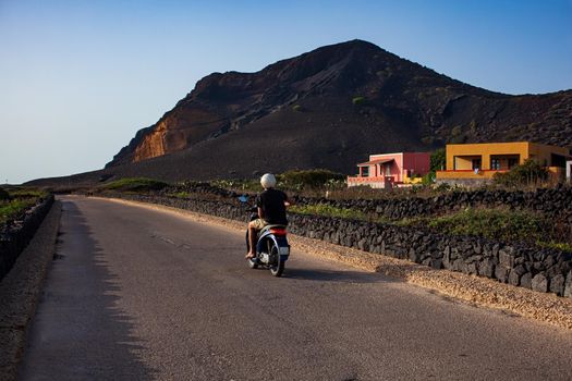 The sightseeing tour by scooter, in the background the Monte Nero famous volcano of Linosa, Sicily. Italy