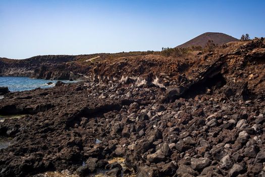 View of the scenic lava rock cliff in the Linosa island. Sicily