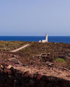 View of lighthouse in the scenic lava rock cliff, Linosa island. Sicily