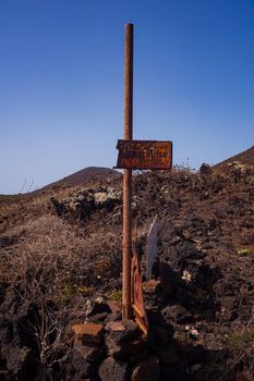 View of an old rusty signage on the lava hill, Linosa. Sicily