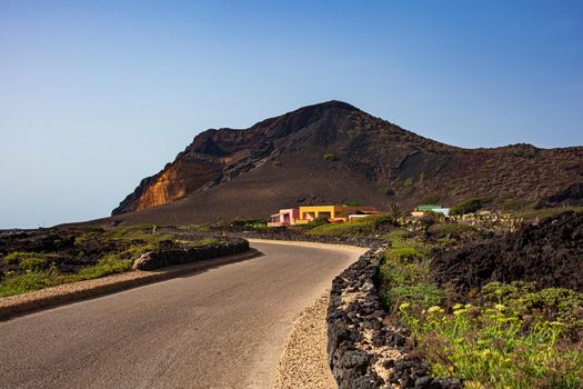 Road with dry stone wall . The Monte Nero Volcano on the background. Linosa, Sicily