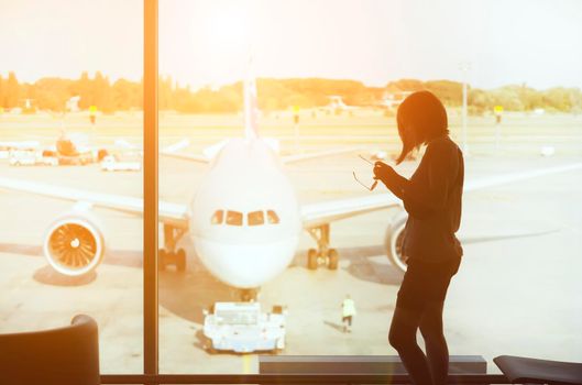 A young girl at the airport is boarding a plane at sunset, a woman goes on a journey.