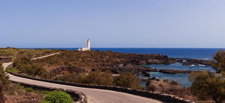 View of lighthouse in the scenic lava rock cliff, Linosa island. Sicily