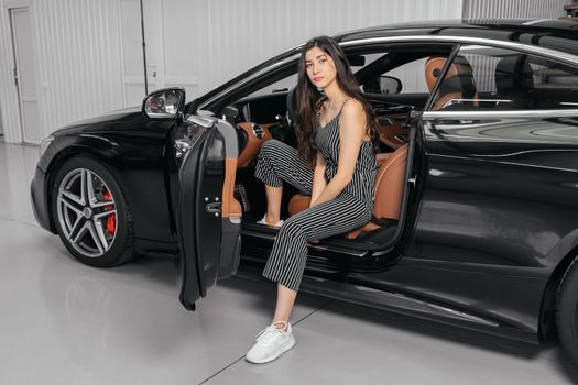 Young asian woman sitting in luxury car in garage before starting engine and driving