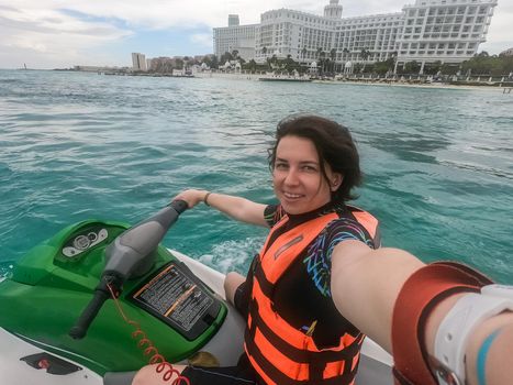 Woman making selfie photo while riding jet ski on Caribbean sea resort. Concept of having fun on summer vacation