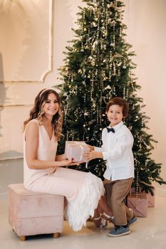 Mom gives her son a Christmas present near the Christmas tree.Happy family.