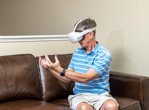 Senior man reaching for object on a modern virtual reality VR headset in home