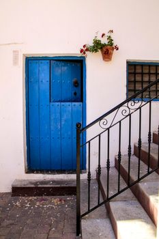 Typical Andalusian whitewashed facade with blue painted wooden door in Mojacar