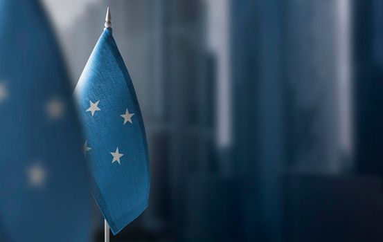 Small flags of Federated States Micronesia on a blurry background of the city.