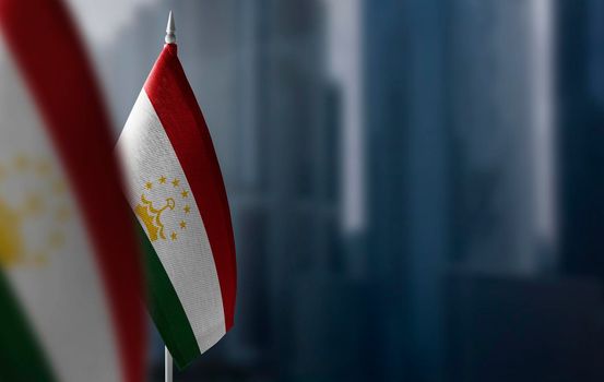 Small flags of Tajikistan on a blurry background of the city.