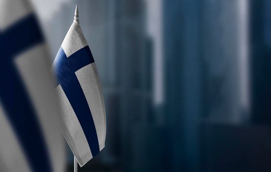 Small flags of Finland on a blurry background of the city.