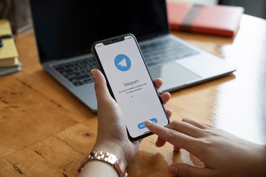 CHIANG MAI, THAILAND, JAN 23, 2021 : Woman hand holding iPhone 12 with social networking service Telegram on the screen. iPhone 12 was created and developed by the Apple inc