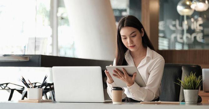 Beautiful business woman using tablet and laptop while working in the office.