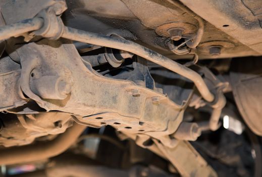 Rusty lower tygi and silent blocks on an old car. In the garage, a man changes parts on a vehicle. Small business concept, car repair and maintenance service. UHD 4K.