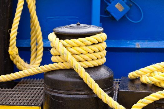 Yellow mooring line coils on black winch marine ship equipment detail